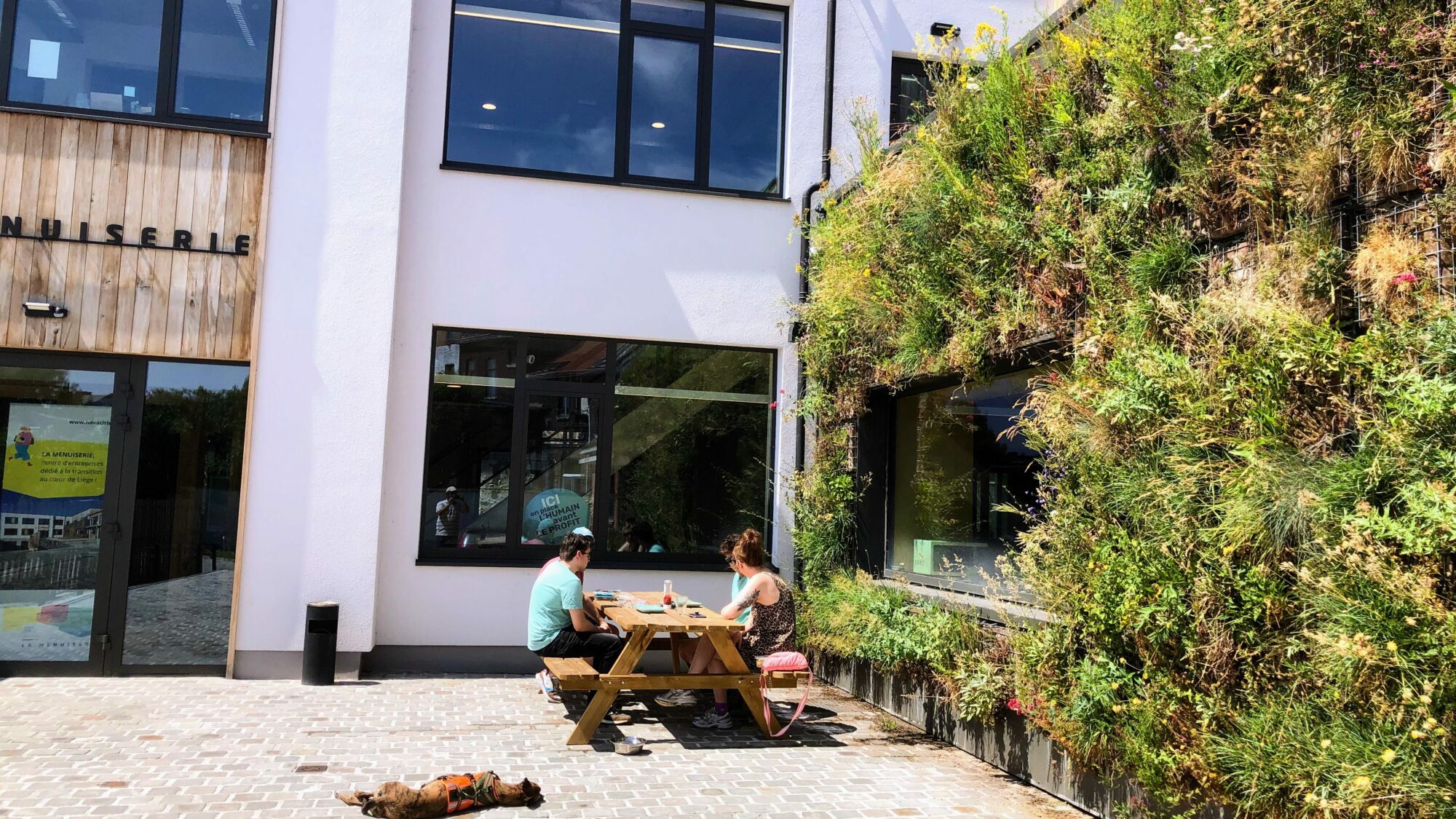 Une façade végétalisée accompagne un espace de rencontre au pied d’un bâtiment